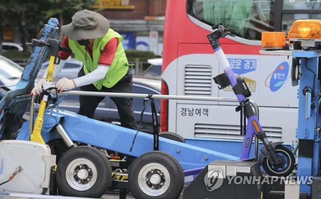 지난 2021년 7월 15일 오전 서울 송파구 가락시장역 인근에서 송파구청 관계자가 불법 주정차된 전동 킥보드를 견인하고 있다. 